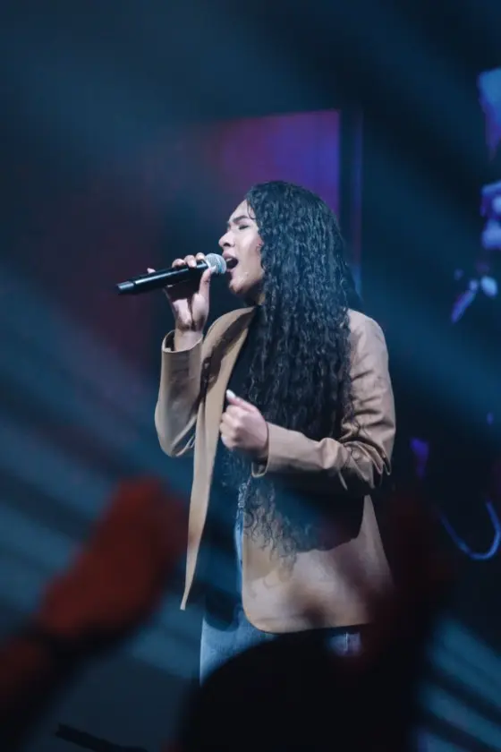 Cantora da Worsheep de olhos fechados cantando ao microfone
